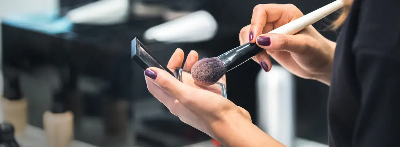Image: hands holding makeup kit. Topic: The Ugly Side of Cosmetics.